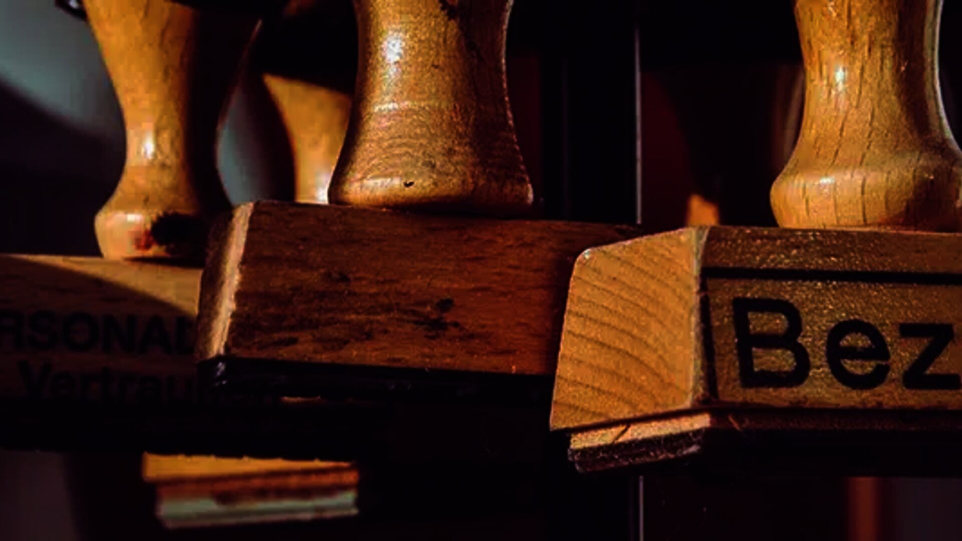 Close-up of wooden stamps, one of which is labeled 'Bezahlt' (Paid in German), symbolizing completed financial transactions