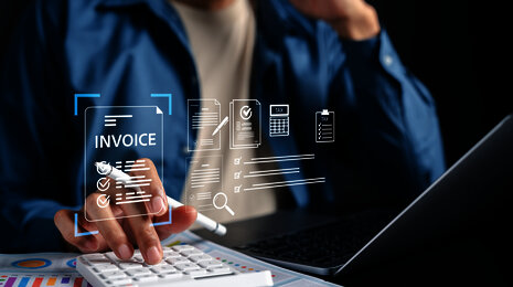 Employee using laptop and calculator with digital symbols for e-invoicing, automated invoice processing and tax documents.