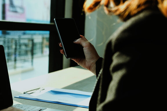 businesswoman holding mobile phone texting message at office