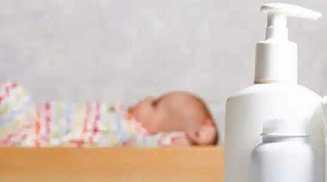 Baby on a bed with lotion and diapers