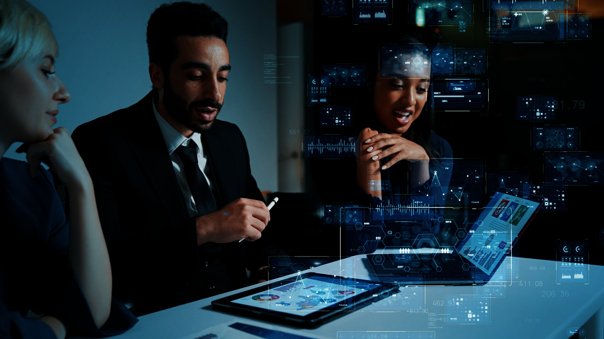 Team of business professionals reviewing data on a laptop and tablet with digital analytics overlays.