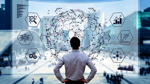 Man standing in front of a large, futuristic digital interface displaying interconnected nodes and hexagonal icons representing various technologies such as data analysis, machine learning, and automation, symbolizing data-driven decision-making and innovation