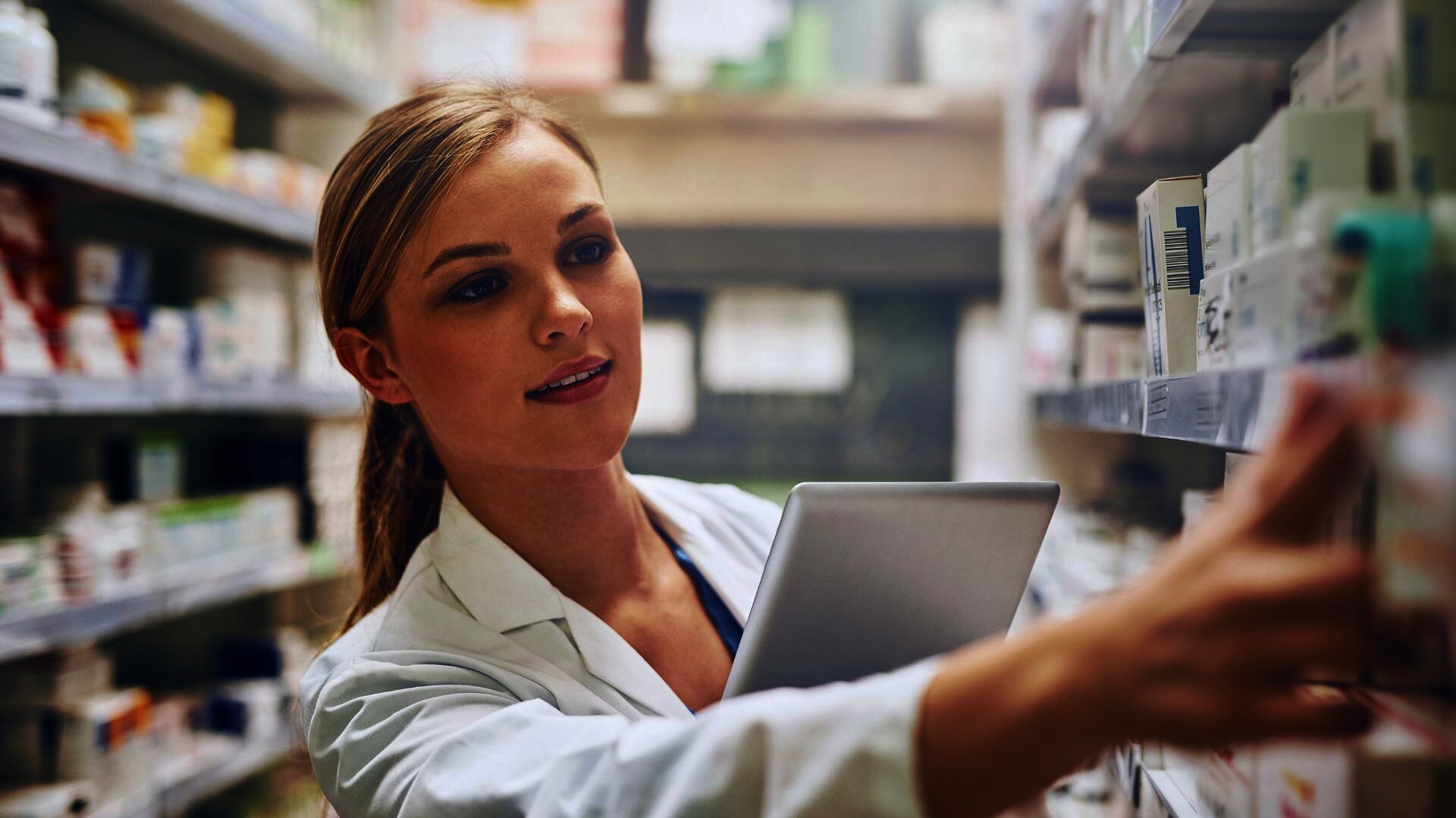 Apothekerin sucht Medikamente in den Regalen