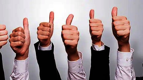 Hands in business attire giving thumbs-up, symbolizing approval, success, or positive feedback