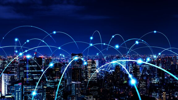 City skyline at night with glowing digital connections, symbolizing global communication and tech