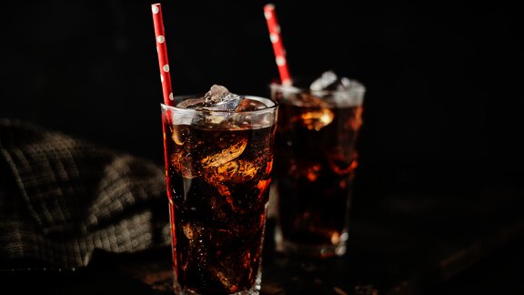 two glasses of coke with ice cubes and straw on the table