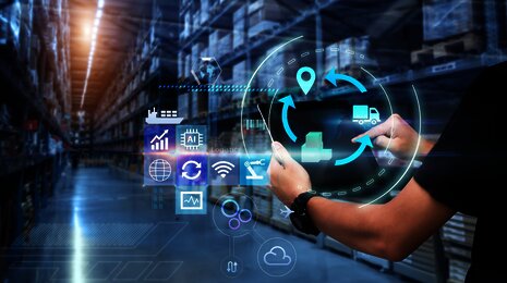 Person using a tablet in a warehouse with overlayed digital logistics and supply chain icons
